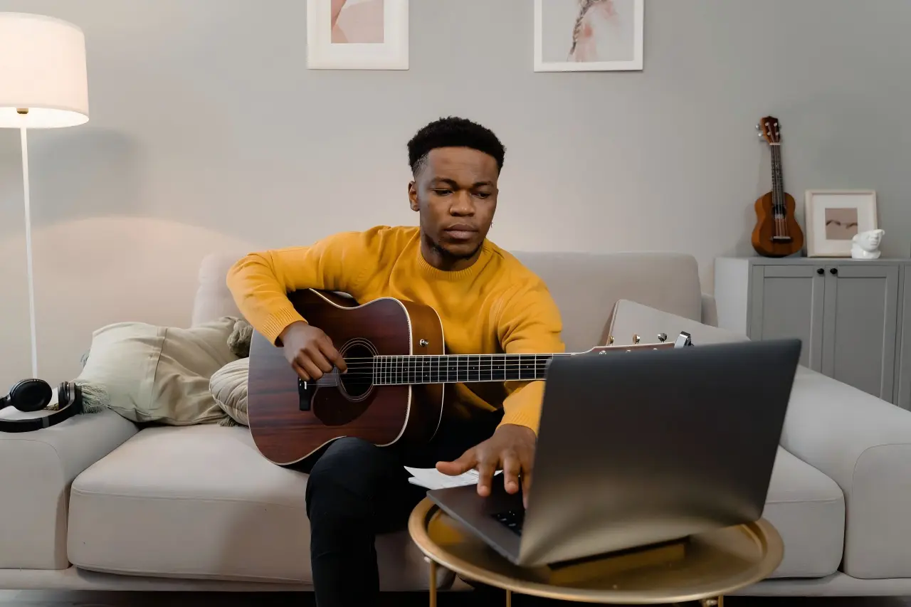 Acoustic guitar beside a laptop showing the EasyTuner online guitar tuner